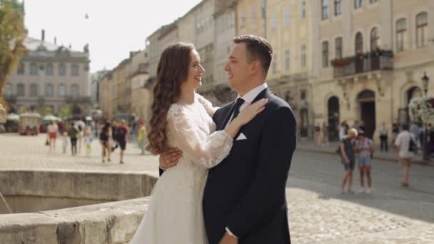 Novomanželé, kavkazský ženich se stojící nevěstou, objímání, objímání na ulici, svatební pár — Stock video