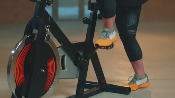 Žena provádí aerobní trénink vytrvalosti kardio rutiny na simulátorech, cyklistický trénink — Stock video