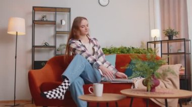 Kafkasyalı genç bir kadın kanepeye oturmuş dizüstü bilgisayarı açıyor ve evdeki oturma odasında çalışmaya başlıyor.