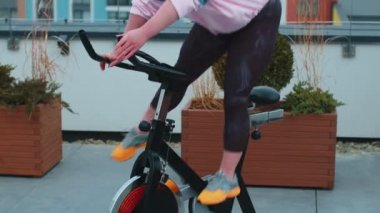 Kadın, simülatörlerde aerobik dayanıklılık antrenmanı, kardiyo çalışması ve bisiklet eğitimi yapıyor.