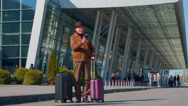 Portret emeryta turystycznego dziadka pobyt w pobliżu hali lotniska czeka na samolot, podróże — Wideo stockowe