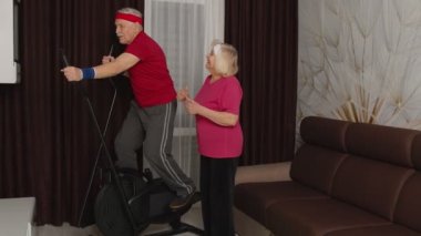 Aktif kıdemli büyükbaba spor giyim bölümünde orbitrek kullanıyor. Büyükannem onu evde cesaretlendiriyor.