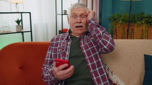 Avô sênior surpreendente usar smartphone móvel, receber mensagem de boas notícias chocado com vitória súbita — Vídeo de Stock