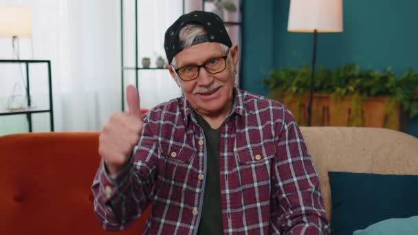 Dziadek staruszek patrząc w kamerę podnosi kciuki w górę zgadza się z czymś pozytywnym w domu — Wideo stockowe