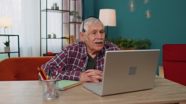 Senior muž na volné noze sluchátka, aby video hovor, výuka na notebooku doma kancelář — Stock video