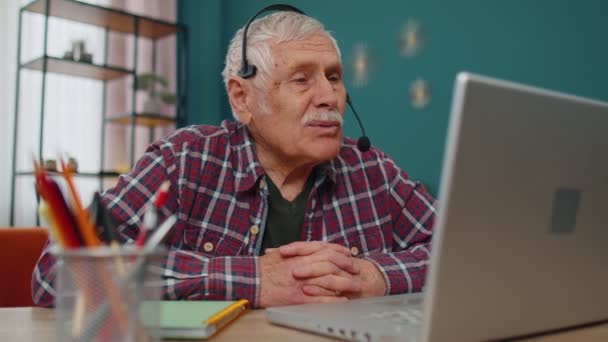 Senior man freelance wear headphone make video call talking, teaching at laptop at home office — 비디오