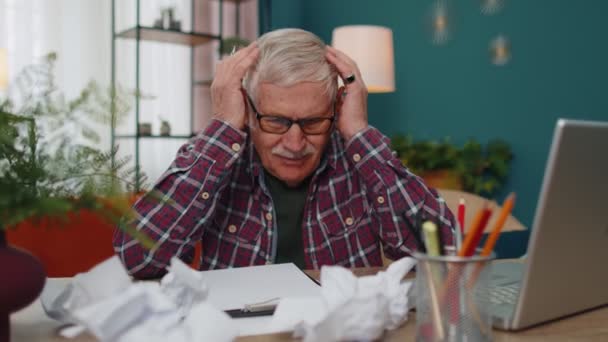 Hombre mayor trabajando en el ordenador portátil, tomando notas en la hoja de papel, molesto por los malos resultados pobres — Vídeo de stock