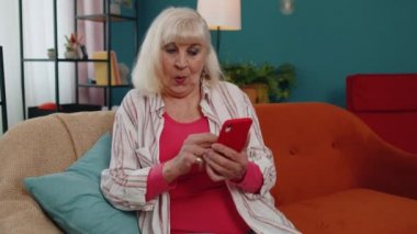 Büyük anne cep telefonunu online alışveriş için kullanır, büyük bir zafer kazanır, evde kutlar.