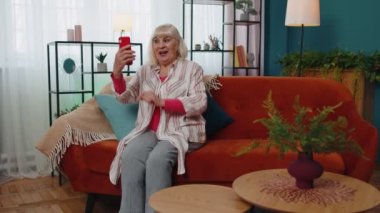 Mutlu son sınıf büyükannesi elinde akıllı telefonuyla cep telefonunu izliyor, internetten arıyor ve selfie çekiyor.