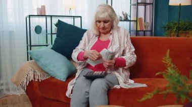 Kıdemli kadın, iç mali faturaları hesaplamak ve aile bütçesini planlamak için para sayıyor.