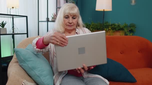 Senior oude grootouder begint te werken op laptop, stuurt berichten, doet online aankopen thuis — Stockvideo