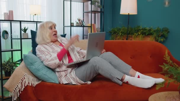 Щаслива старша бабуся з ноутбуком святкує успіх вигравайте гроші в лотереї онлайн хороші новини — стокове відео