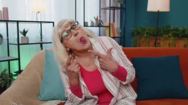 Yaşlı büyük anne aptalca surat ifadeleri takınıyor, suratını buruşturuyor, aylaklık ediyor, dil gösteriyor.