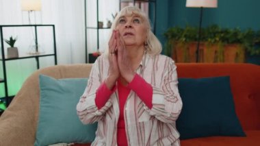 Üzgün yaşlı kadın dua ediyor, yukarı bakıyor, dilek diliyor, özür diliyor, evde yardım istiyor.