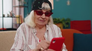 Büyük anne cep telefonunu online alışveriş için kullanır, büyük bir zafer kazanır, evde kutlar.