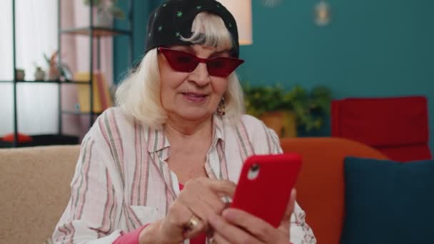 Senior γιαγιά χρησιμοποιούν κινητό τηλέφωνο online ψώνια, ανακάλυψε μεγάλη νίκη, γιορτάζουν στο σπίτι — Αρχείο Βίντεο