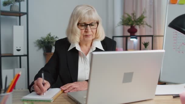 Senior mature plus âgée femme de bureau d'affaires elearning notes d'écriture en ligne de l'ordinateur portable, webinaire en direct — Video