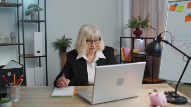 Senior volwassen oudere kantoor vrouw elearning online schrijven notities van laptop, live webinar — Stockvideo