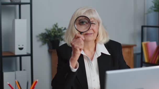 Starší obchodní žena se dívá přes lupu, vyšetřovat, zkoumat, analyzovat, číst — Stock video