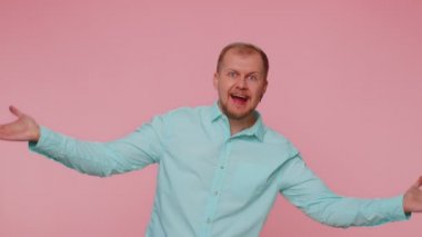 Sakallı adam kameraya dostça gülümsüyor ve el sallıyor.