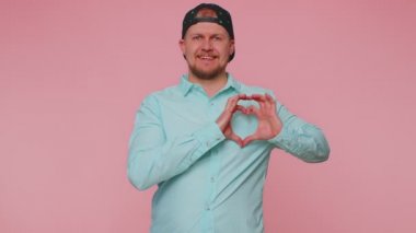 Gülümseyen adam kalp hareketi yapar. Aşk işareti iyi duygular ve sempati gösterir.