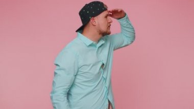 Sakallı adam kameraya dostça gülümsüyor ve el sallıyor.