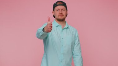 Dost canlısı bir adam kameraya uzanıyor, el sıkışmayı teklif ediyor, nazik bir gülümsemeyle selamlıyor, hoş karşılıyor.