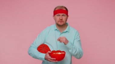 Sakallı genç basketbol fanatiği patlamış mısır yiyor. Jest yapıyor, zaferi kutluyor.