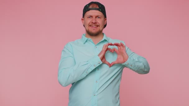 Lachende man maakt hart gebaar toont liefde teken drukt goede gevoelens en sympathie — Stockvideo