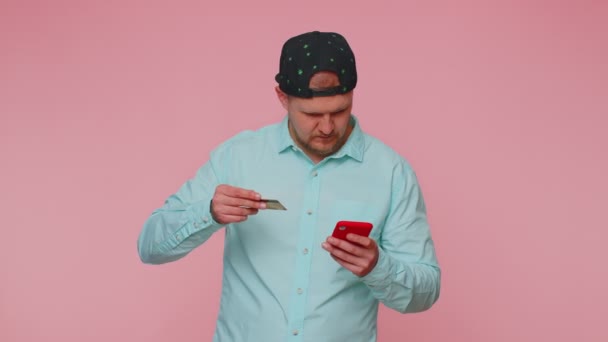 男は携帯電話とプラスチッククレジットカードを使用して、ブラウジングはいすごいと言う大きな勝利を発見 — ストック動画