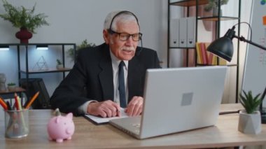 Kulaklık takan kıdemli işadamı laptopta konferans videosu çekiyor, çağrı merkezi ajanı, operatör.