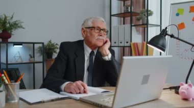 Kıdemli iş adamı mali tabloları analiz ediyor. Ev işyeri masasında kazanılan başarıyı kutluyor.