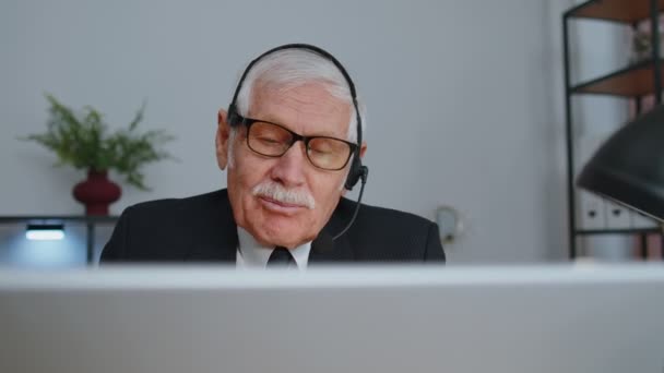 Senior oude zakenman draagt headset werkend in kantoor, call center, conferentie, support agent — Stockvideo