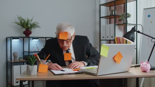 Fáradt kimerült idősebb üzletember irodavezető laptoppal ragacsos jegyzetek botok sok feladat — Stock videók