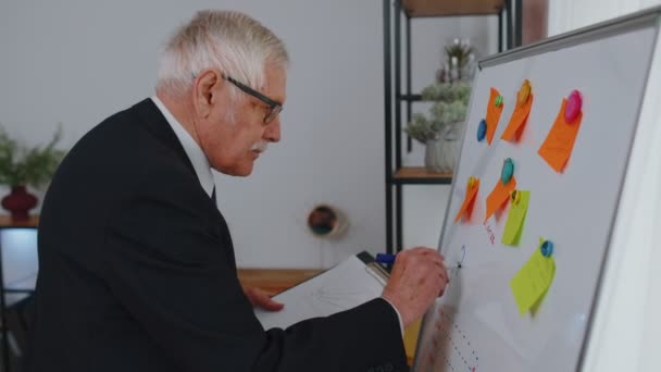 Senior business man making notes on board with stickers analyzing infographics use laptop computer — Stock Video