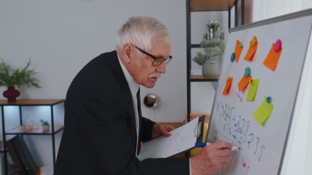 Senior business man making notes on board with stickers analyzing infographics use laptop computer — Vídeo de Stock