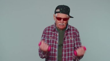 Elderly senior man making fitness exercises with dumbbells alone, working out pumping up arm muscles