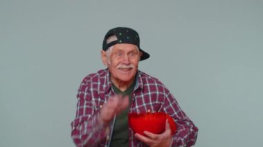 Yaşlı yaşlı basketbol fanatiği patlamış mısır yiyor kazanan hareketi yapıyor, zaferi kutluyor.