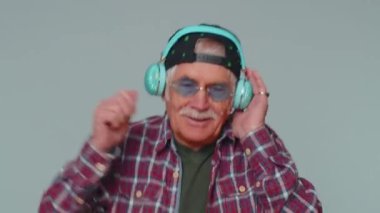 Neşeli çekici adam kulaklıkla müzik dinliyor ve dans edip eğleniyor.