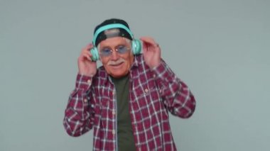 Neşeli çekici adam kulaklıkla müzik dinliyor ve dans edip eğleniyor.