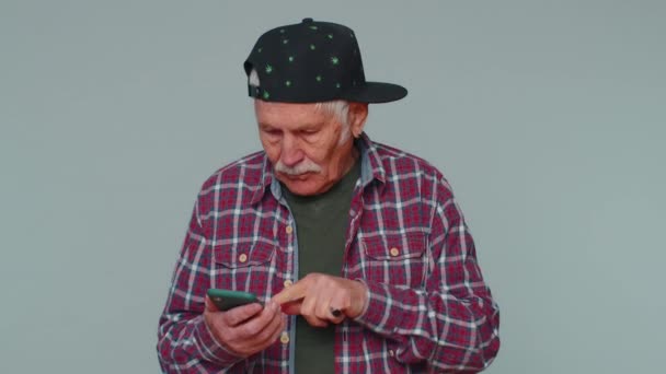 Feliz emocionado viejo uso de teléfono móvil decir wow sí se enteró de grandes noticias ganar haciendo gesto ganador — Vídeos de Stock