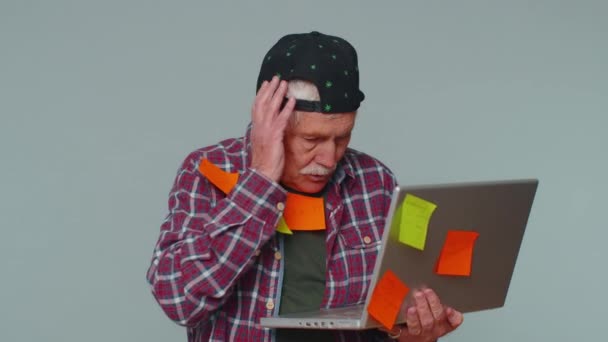 Exhausted senior man with pasted stickers use laptop computer, concentration problem creative crisis — стоковое видео