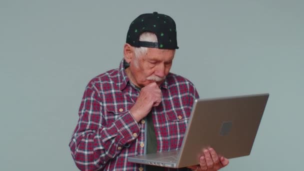 Happy senior man typing on laptop computer, working on project, enjoying results, winning lottery — Stockvideo