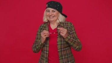 Baştan çıkarıcı neşeli stil sahibi yaşlı kadın güneş gözlüğü takıyor, büyüleyici bir gülümseme, göz kırpıyor.