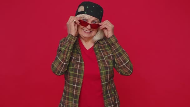 Seductive cheerful stylish senior old woman wearing sunglasses, charming smile, blinks winks eyes — Vídeo de stock