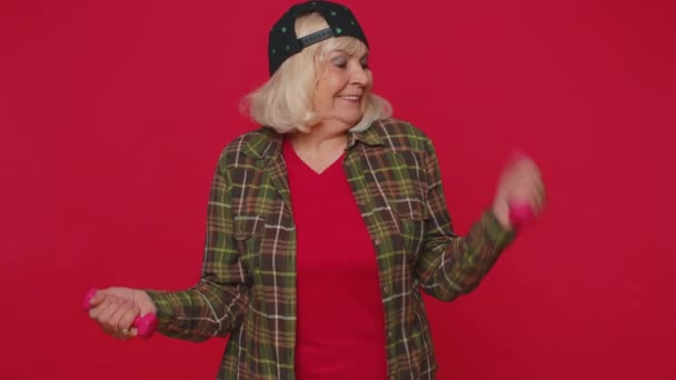 Starsza starsza pani robi ćwiczenia fitness z hantlami, ćwiczy pompowanie mięśni ramion — Wideo stockowe