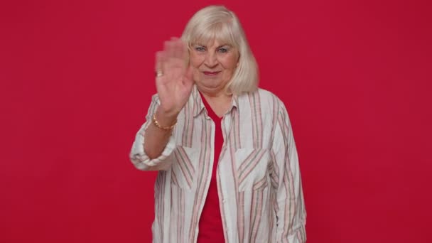 Starší žena se přátelsky usmívá na kameru a mává rukama gestikuluje ahoj nebo sbohem, vítá — Stock video