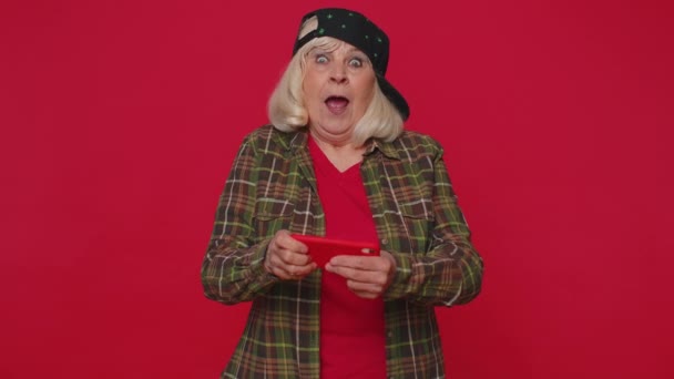 Bezorgd grappige verslaafde oudere vrouw enthousiast spelen drive racing video games op mobiele telefoon — Stockvideo