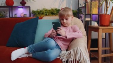 Küçük liseli kız akıllı telefon sörfü yapıyor, online oyun oynuyor, arkadaşlarıyla sohbet ediyor.