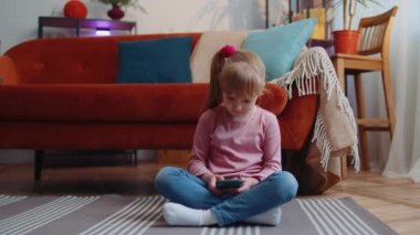 Heyecanlı kazanan kız cep telefonu kullanıyor ve evet diyor evde tek başına sürpriz bir şekilde el kaldırıyor.